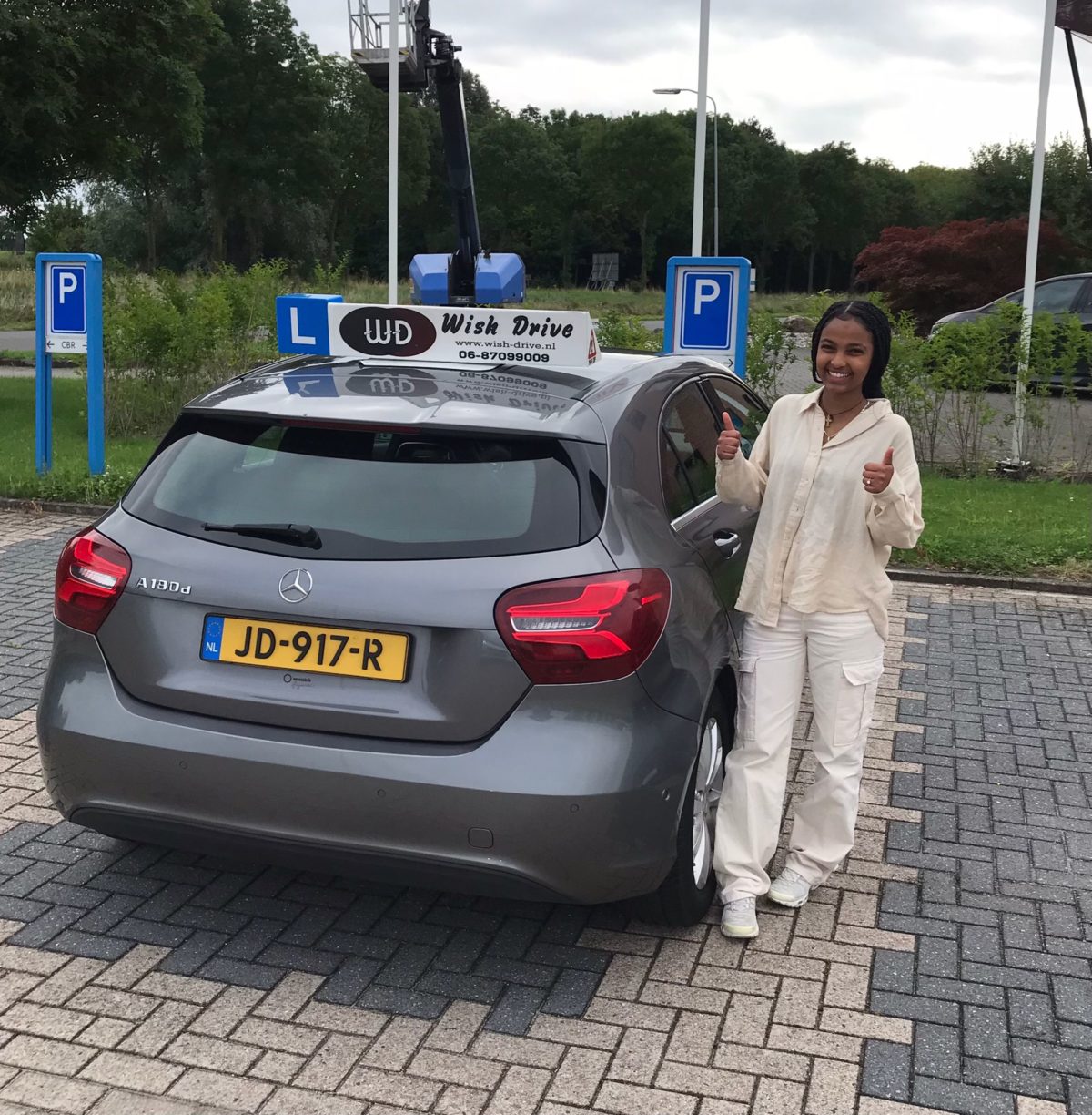 Blije geslaagde leerling naast de lesauto van Wish Drive